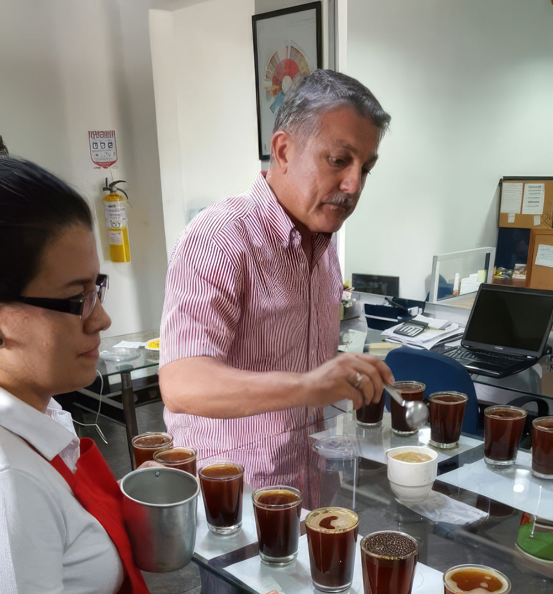 Kolumbianischer Kaffeebauer bei einer professionellen Kaffeeverkostung mit verschiedenen Röstproben – Qualitätsprüfung und Auswahl von Kaffeebohnen für Lena & Louise Coffees.