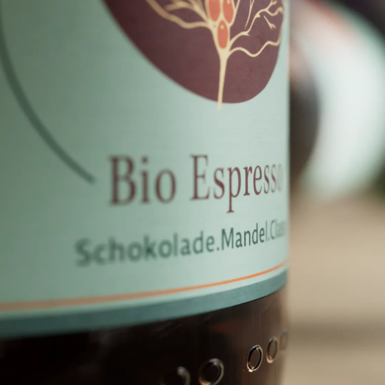 Bio Espresso von Lena & Louise Coffees mit Schokoladen- und Mandelnoten – Detailaufnahme des Kaffeeetiketts auf der Mehrwegflasche.